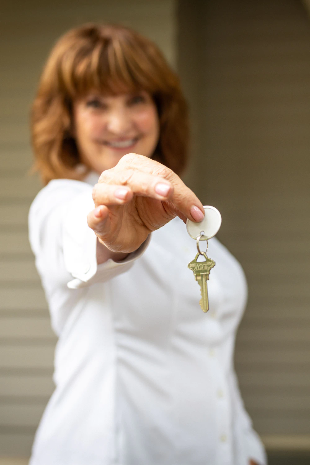 Tracy in front of North End home holding out keys for new owner